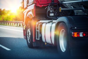 Red Semi Truck Speeding on a Highway. Tractor Closeup. Transportation and Logistics Theme.